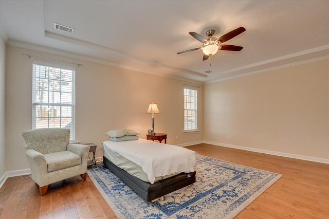 bedroom featuring hardwood / wood-style floors, ornamental molding, a raised ceiling, and ceiling fan