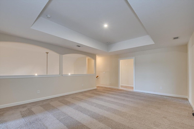 carpeted spare room with a raised ceiling