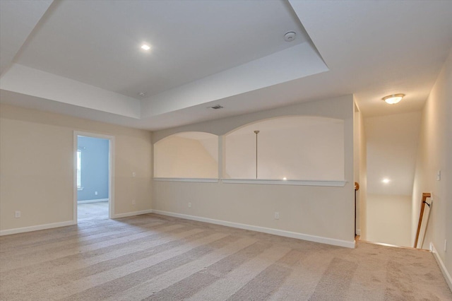 carpeted spare room featuring a raised ceiling