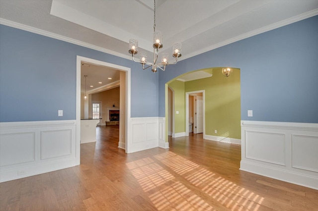 spare room featuring a notable chandelier, crown molding, and light hardwood / wood-style floors