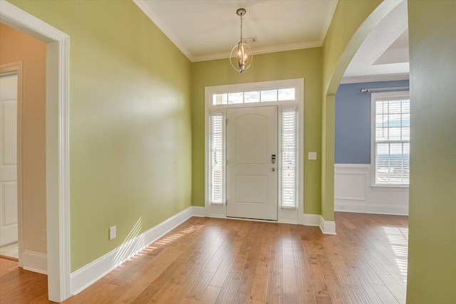 entryway with ornamental molding and light hardwood / wood-style flooring