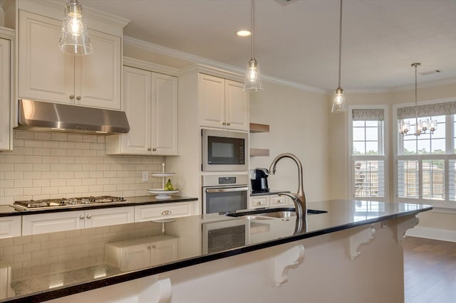 kitchen featuring pendant lighting, tasteful backsplash, sink, dark stone counters, and stainless steel appliances