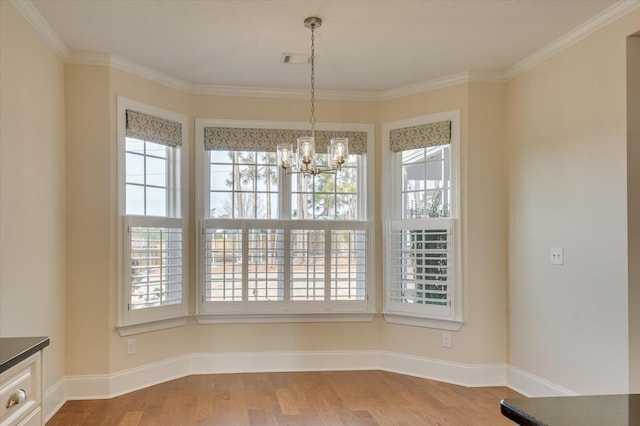 unfurnished dining area with hardwood / wood-style flooring, ornamental molding, and a chandelier