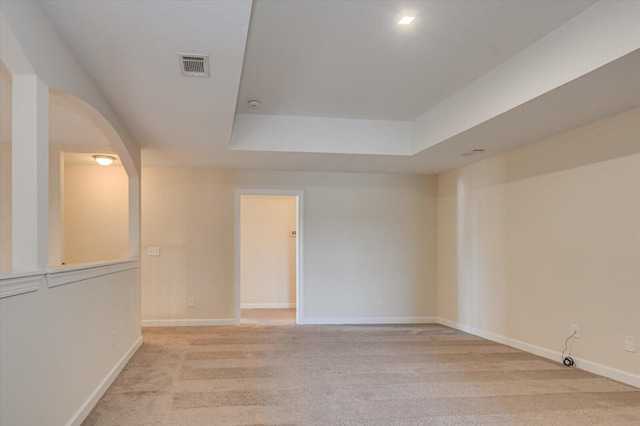 spare room featuring light colored carpet and a tray ceiling