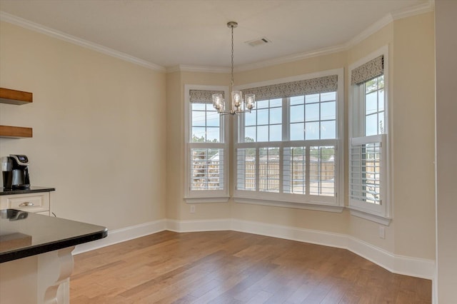 unfurnished dining area with a notable chandelier, crown molding, and light hardwood / wood-style flooring