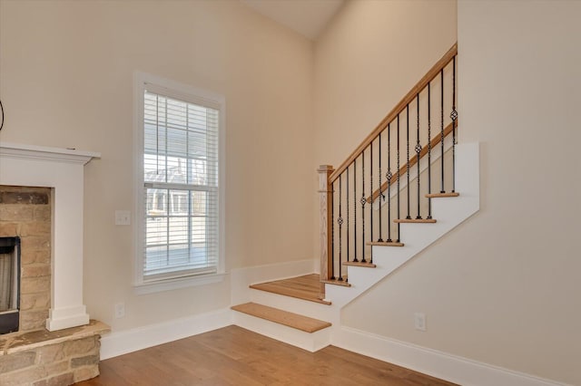 stairway featuring a fireplace, hardwood / wood-style flooring, and plenty of natural light