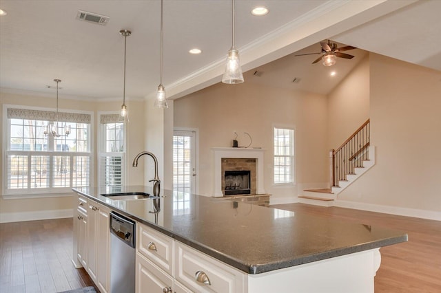 kitchen featuring sink, dishwasher, an island with sink, white cabinets, and decorative light fixtures