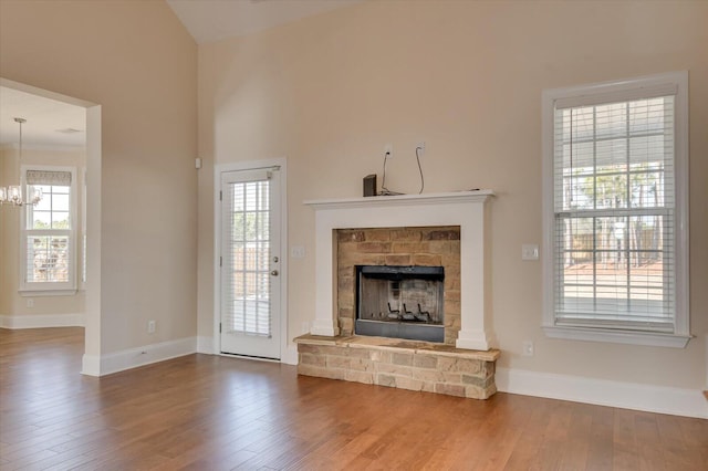 unfurnished living room featuring an inviting chandelier, hardwood / wood-style floors, and plenty of natural light