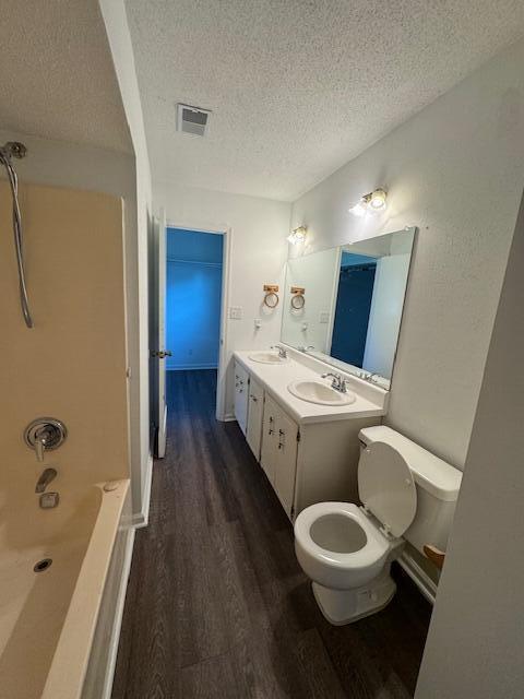6183 Columbia Rd, Appling, GA 30802 - full bath with wood finished floors, a textured ceiling, double vanity, and shower / tub combination