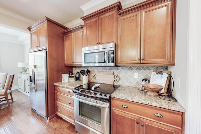617 Morris Run, North Augusta, SC 29860 - kitchen featuring appliances with stainless steel finishes, tasteful backsplash, light stone counters, light wood-style flooring, and brown cabinetry