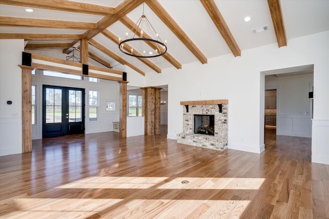 unfurnished living room with french doors, a fireplace, light hardwood / wood-style flooring, high vaulted ceiling, and beamed ceiling