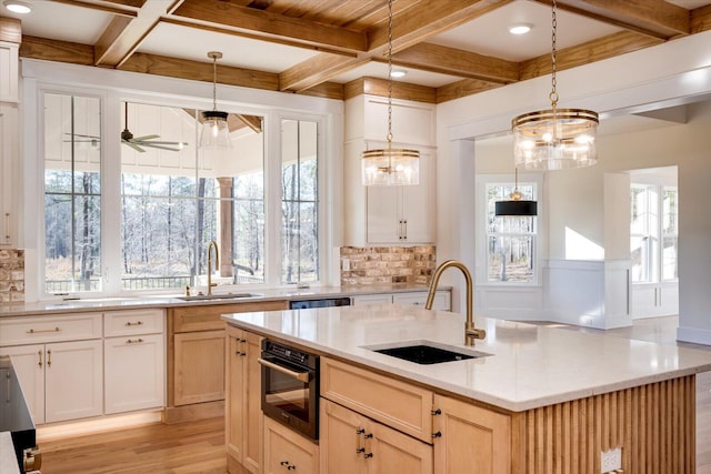 kitchen with backsplash, oven, a kitchen island with sink, and sink