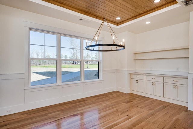 unfurnished dining area with an inviting chandelier, a tray ceiling, light hardwood / wood-style flooring, and wooden ceiling