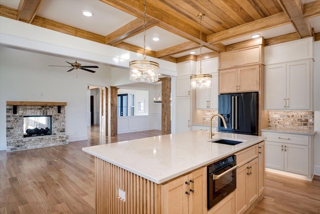 kitchen with sink, a kitchen island with sink, high end refrigerator, pendant lighting, and decorative backsplash