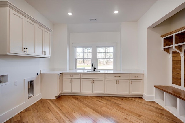 clothes washing area with sink, washer hookup, cabinets, hookup for an electric dryer, and light hardwood / wood-style flooring