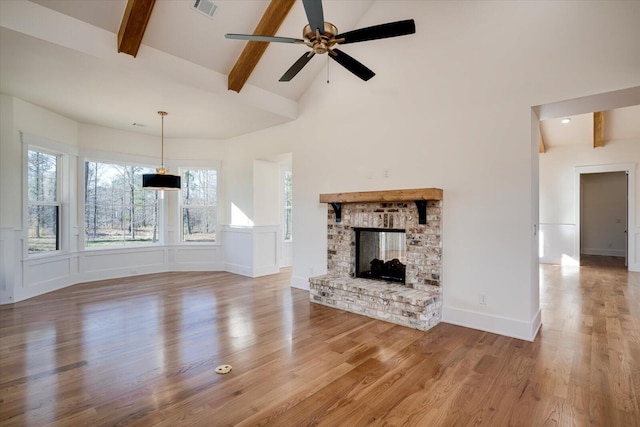 unfurnished living room featuring high vaulted ceiling, hardwood / wood-style flooring, ceiling fan, a fireplace, and beam ceiling