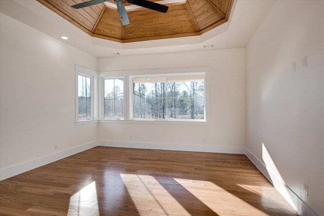 spare room featuring a skylight, ceiling fan, wooden ceiling, a raised ceiling, and light hardwood / wood-style floors
