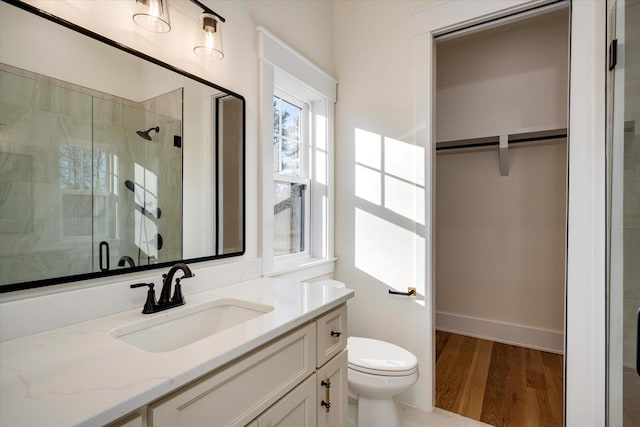 bathroom with walk in shower, toilet, vanity, and hardwood / wood-style flooring