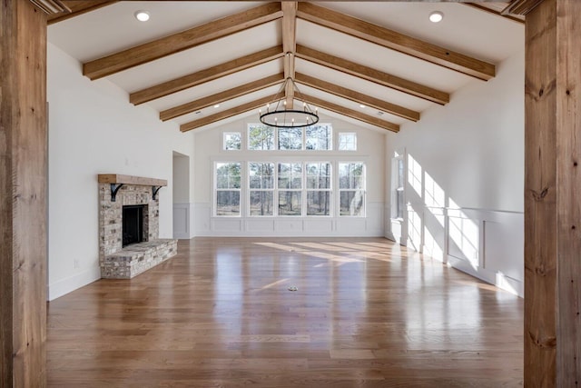 unfurnished living room with a fireplace, hardwood / wood-style floors, high vaulted ceiling, and beamed ceiling