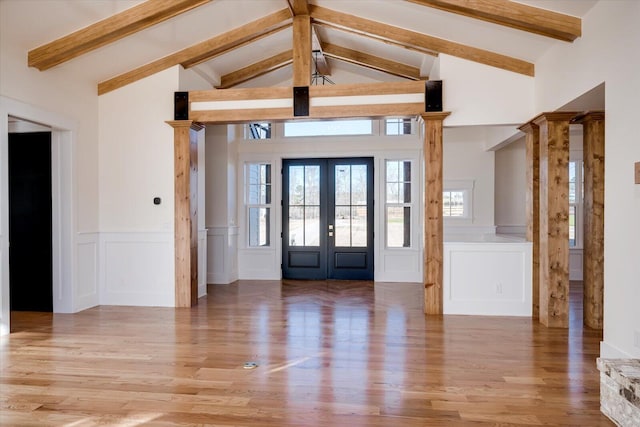 foyer entrance with lofted ceiling with beams, light hardwood / wood-style floors, decorative columns, and french doors