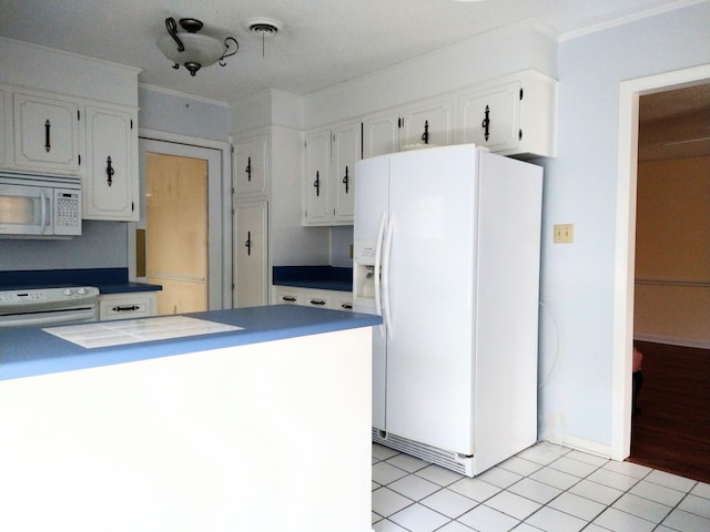 kitchen featuring white appliances, white cabinets, light tile patterned flooring, dark countertops, and crown molding