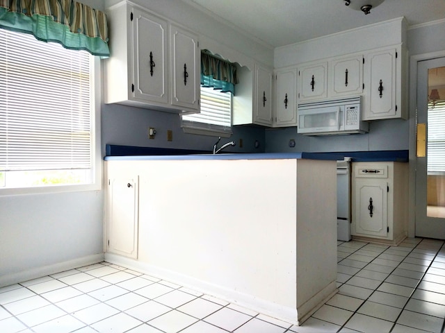kitchen with white microwave, white cabinets, light tile patterned flooring, crown molding, and a peninsula