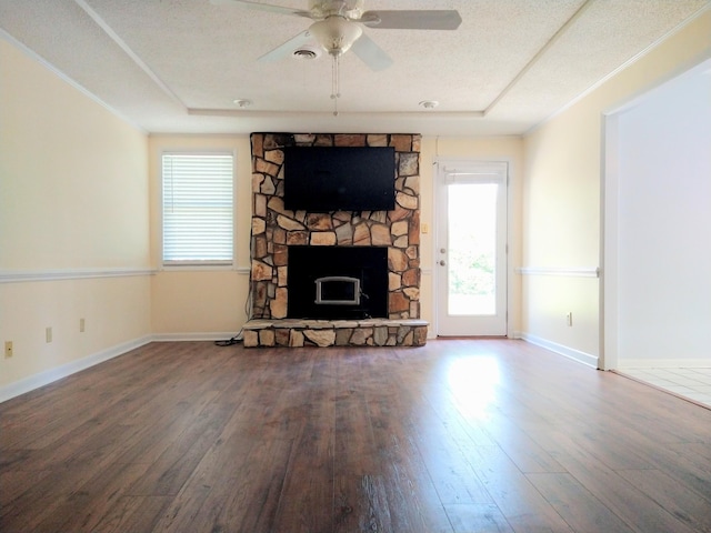 unfurnished living room featuring wood-type flooring, a stone fireplace, a ceiling fan, and baseboards