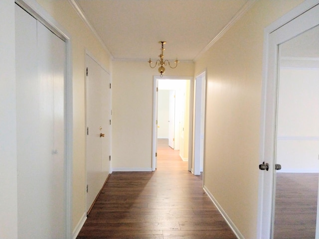 corridor featuring ornamental molding, wood finished floors, a chandelier, and baseboards