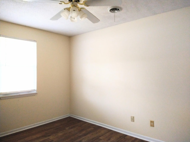 spare room featuring dark wood finished floors, ceiling fan, and baseboards