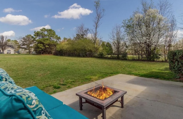 view of green lawn with a patio area and an outdoor fire pit
