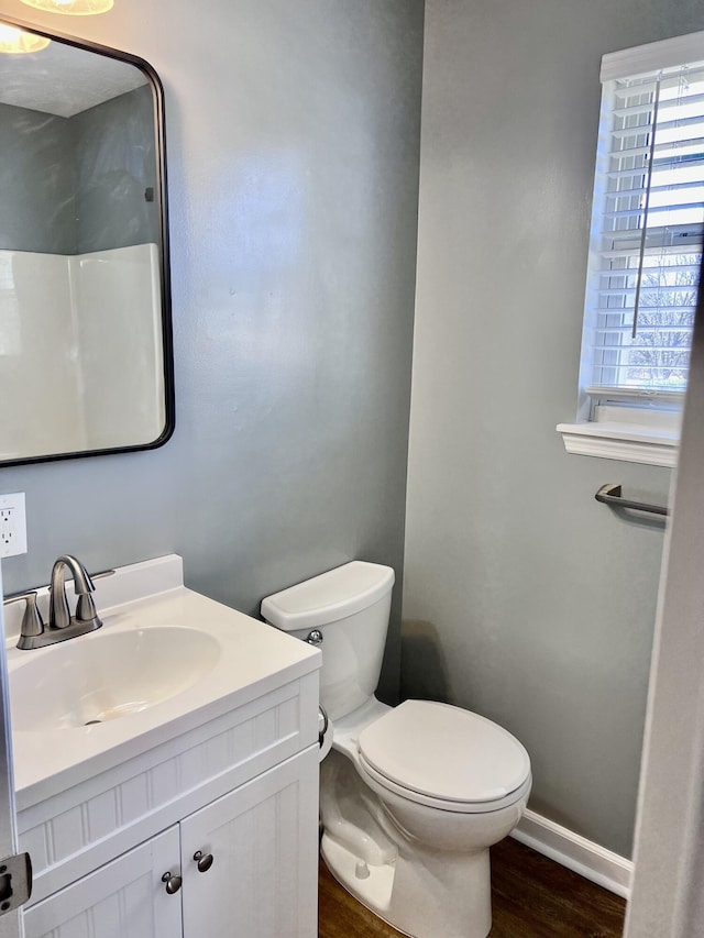 bathroom featuring toilet, wood finished floors, vanity, and baseboards