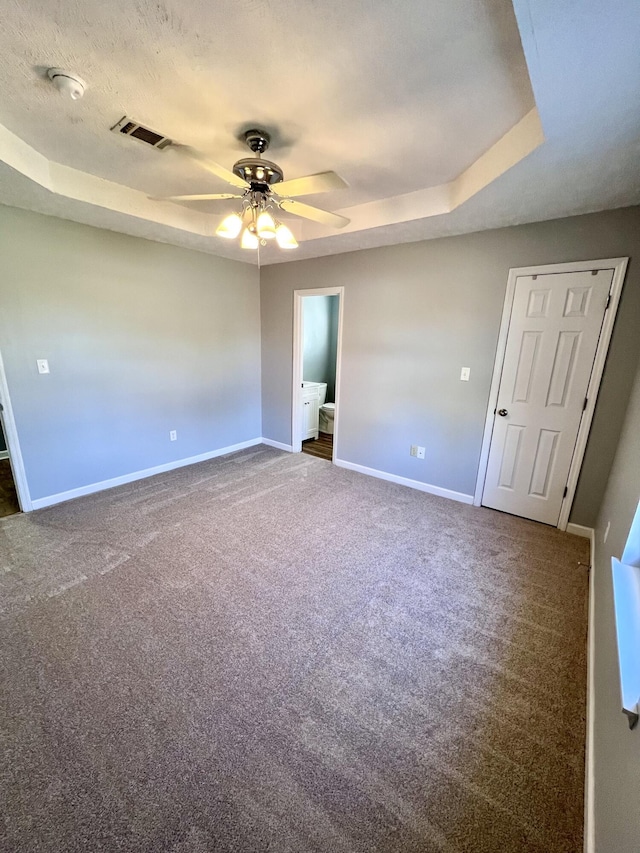 spare room featuring a ceiling fan, baseboards, carpet, and a tray ceiling