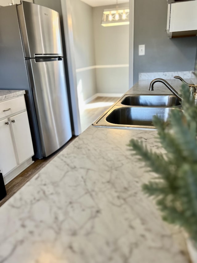 kitchen featuring freestanding refrigerator, a sink, white cabinets, and wood finished floors