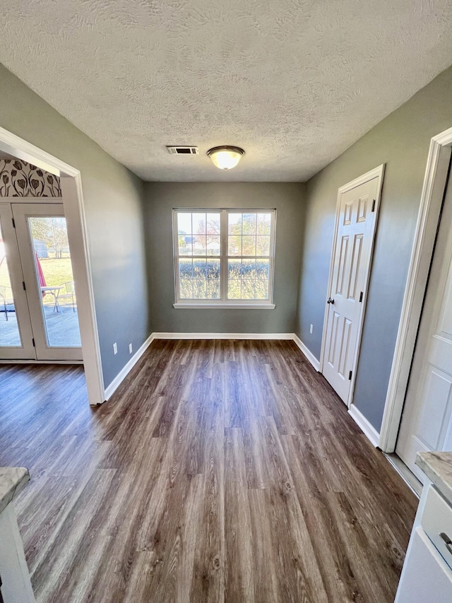 unfurnished dining area with dark wood-style floors, baseboards, and a textured ceiling