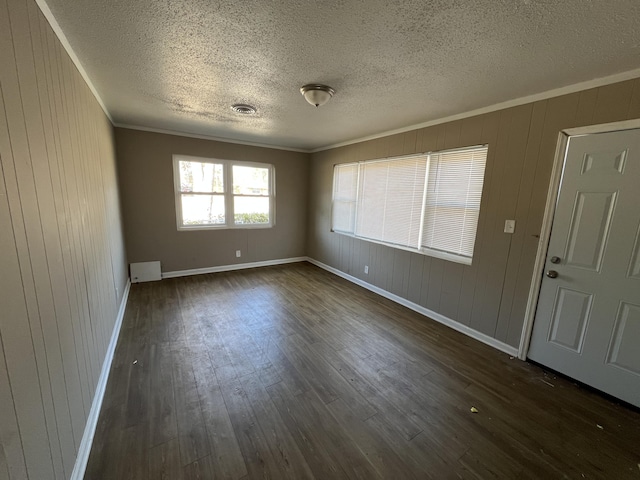 spare room with crown molding, dark hardwood / wood-style flooring, and a textured ceiling