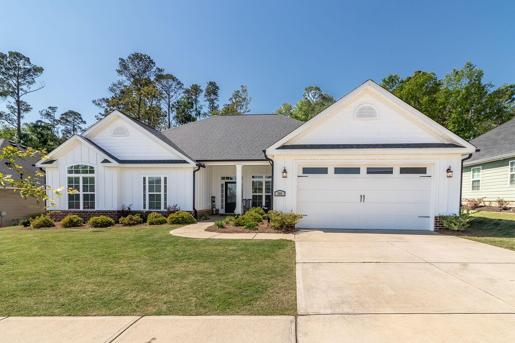 306 Bonhill St, North Augusta, SC 29860 - view of front of home with concrete driveway, board and batten siding, roof with shingles, a front yard, and a garage