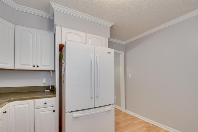 160 Crescent Dr, Mccormick, SC 29835 - kitchen with freestanding refrigerator, light wood-type flooring, white cabinetry, dark countertops, and crown molding