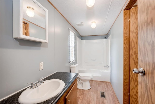 full bathroom featuring vanity, hardwood / wood-style floors, a textured ceiling, toilet, and shower / bathing tub combination