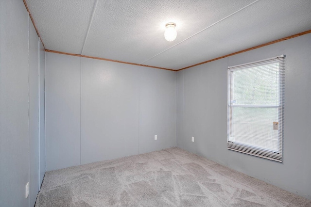 unfurnished room with light carpet, a textured ceiling, and ornamental molding