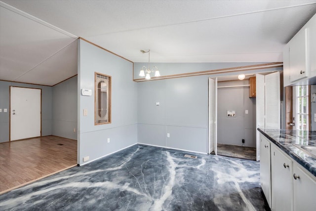 interior space with white cabinets, decorative light fixtures, an inviting chandelier, and vaulted ceiling