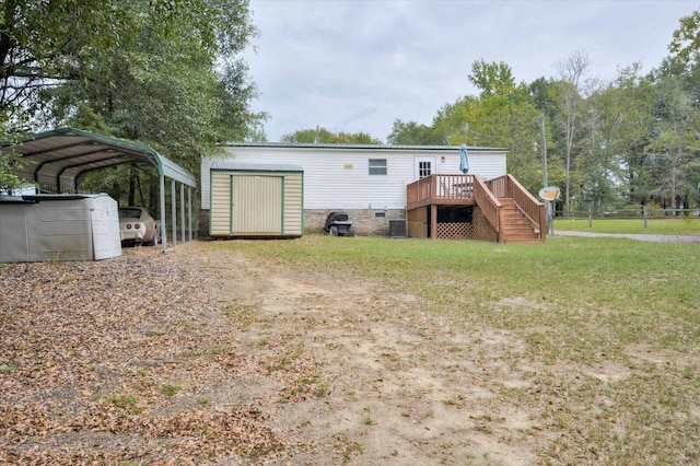 back of property with a lawn, central air condition unit, a carport, a wooden deck, and a storage unit