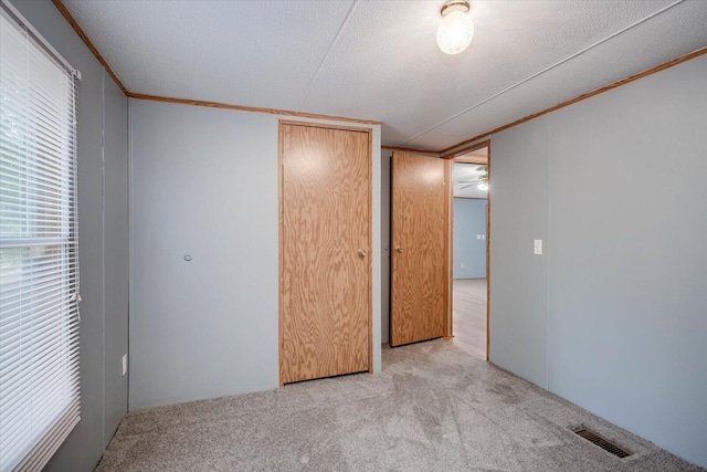 unfurnished bedroom with a textured ceiling, light carpet, and a closet