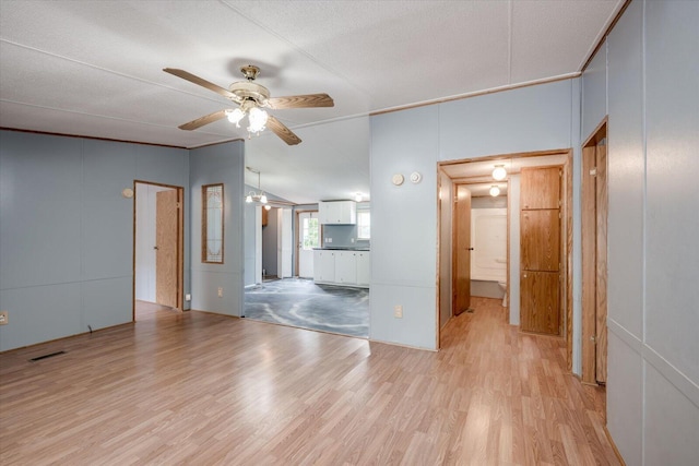 unfurnished living room with ceiling fan, light wood-type flooring, and a textured ceiling