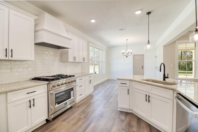 kitchen featuring premium range hood, visible vents, a sink, stainless steel appliances, and crown molding