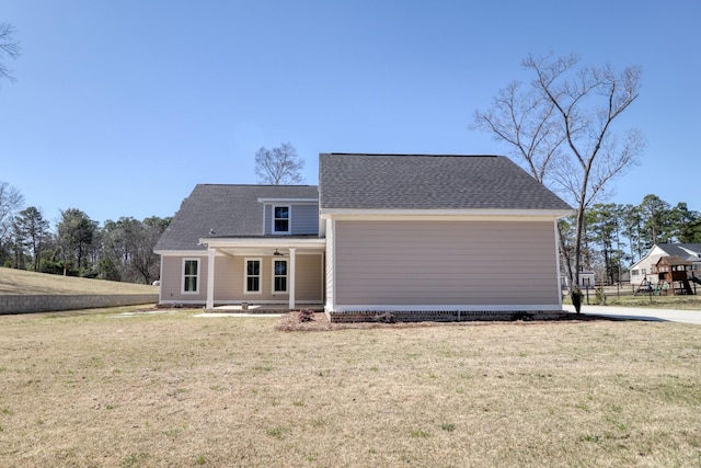 view of front of house featuring covered porch, a front yard, and a shingled roof