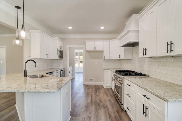 kitchen featuring appliances with stainless steel finishes, a peninsula, wood finished floors, custom exhaust hood, and a sink