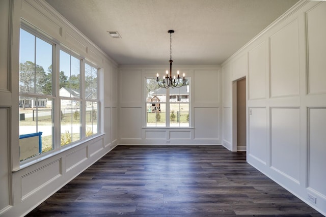 unfurnished dining area featuring visible vents, dark wood-type flooring, a chandelier, and a decorative wall