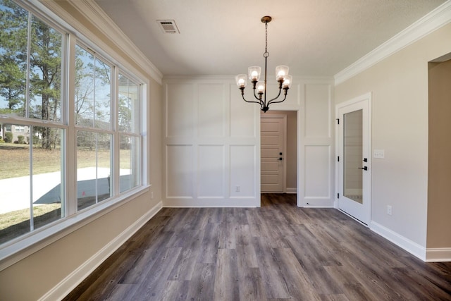 unfurnished dining area with dark wood-style floors, visible vents, an inviting chandelier, crown molding, and a decorative wall