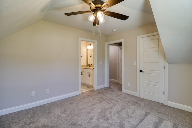 unfurnished bedroom with lofted ceiling, light colored carpet, baseboards, and ensuite bathroom