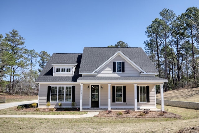 view of front of property with a porch, a front yard, and a shingled roof